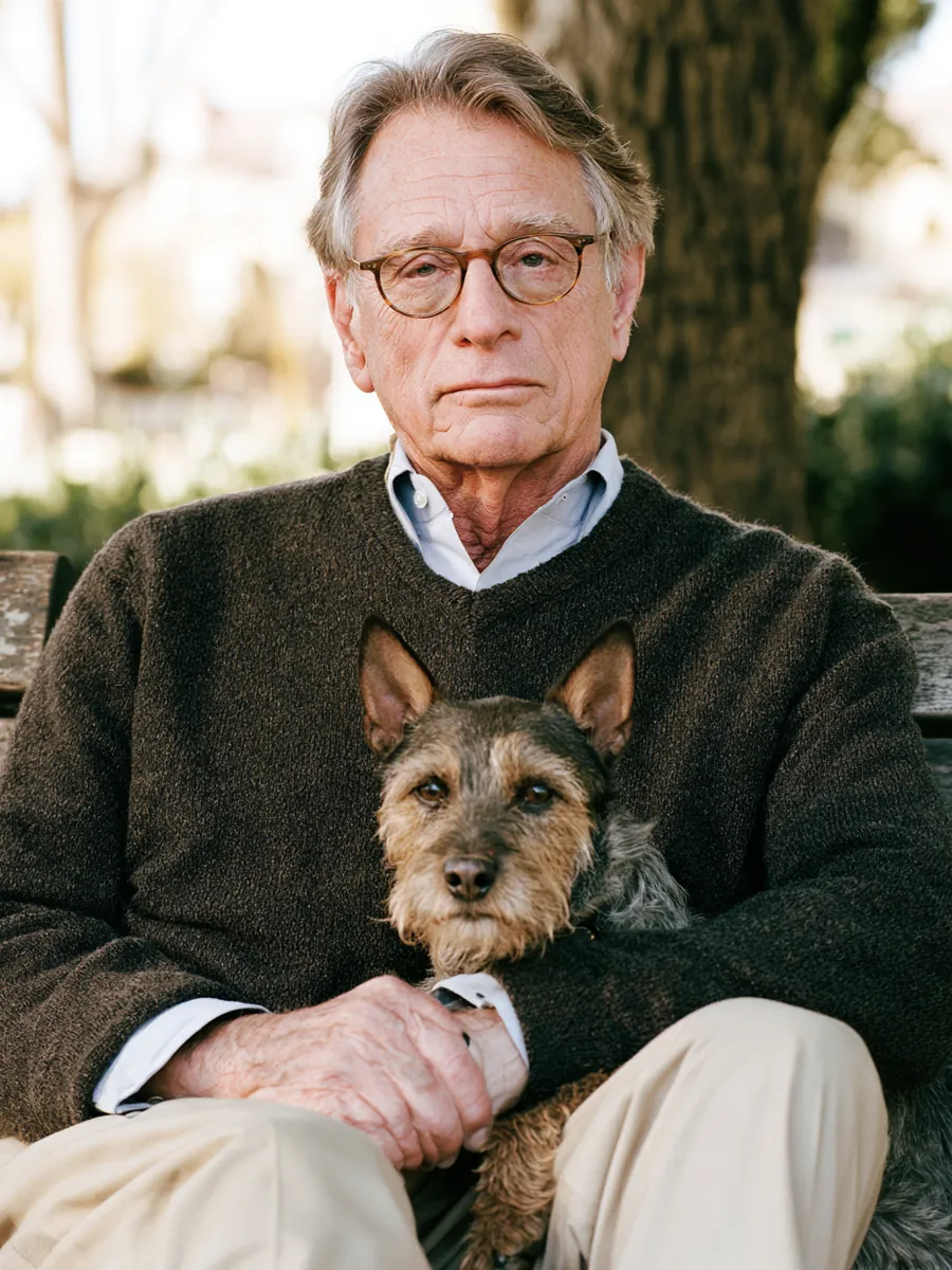 Man in his 60s relaxing on a park bench with his terrier leaning against him in afternoon sun