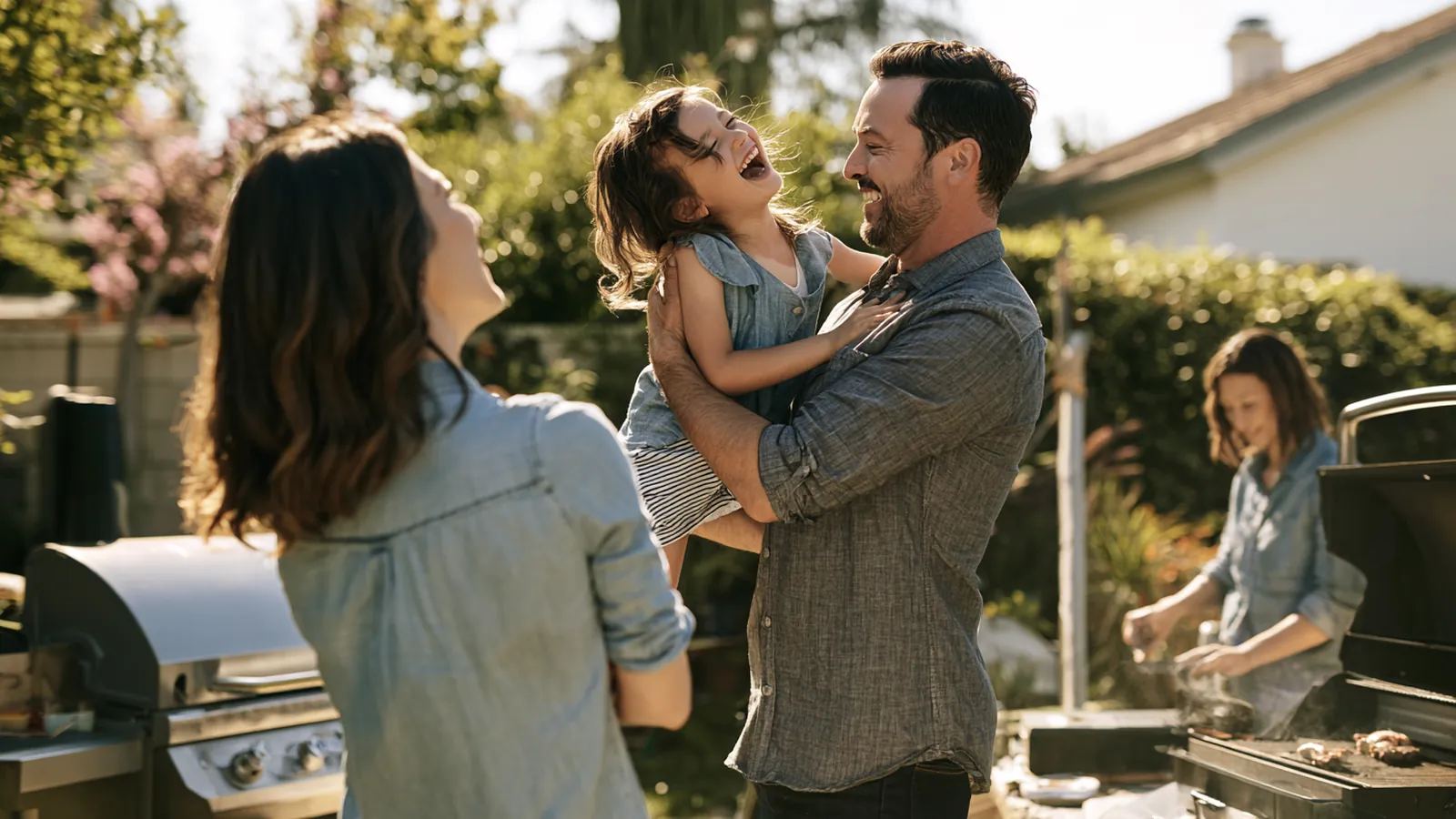 Father lifting his laughing daughter in a tidy backyard while the family grills, the everyday life personal loans support